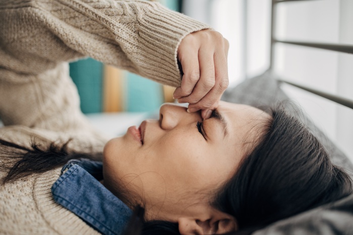 A woman with a headache closes her eyes in a Houston, TX emergency room