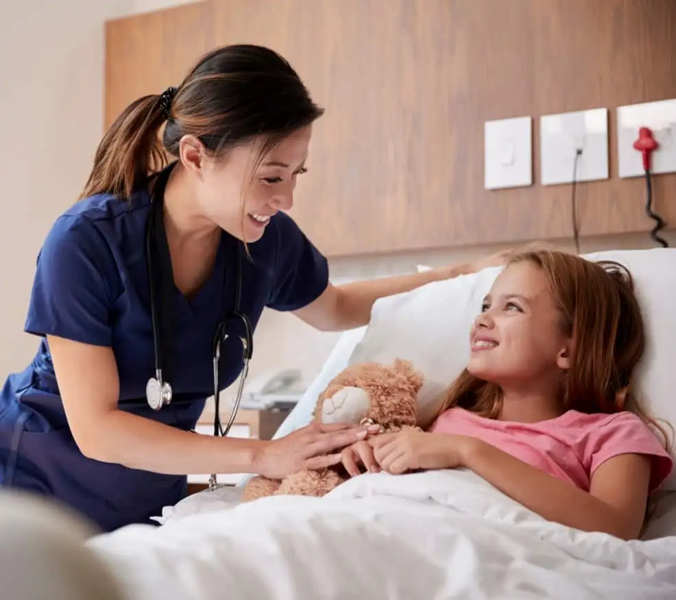 A young female patient holds a bear in her emergency room bed in Houston, TX