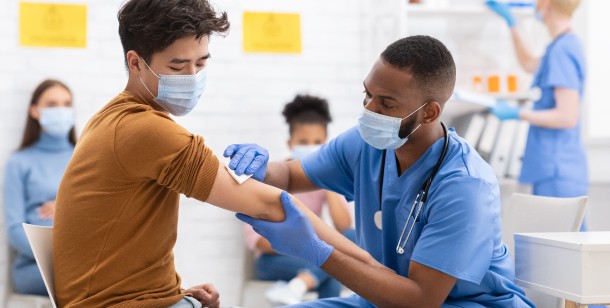 A doctor cleans a patient's arm before giving him a COVID-19 vaccine