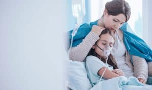 A mom holding her child with pneumonia in an emergency room in Houston, TX