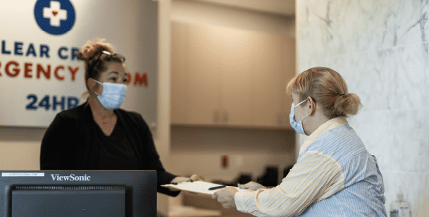 A woman hands in her paperwork at an emergency room in Houston, TX