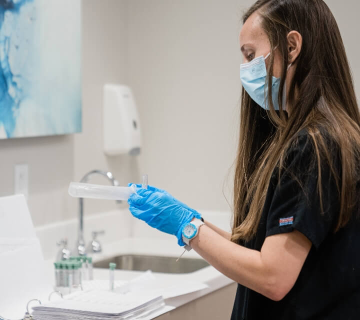 A doctor wears a face mask and gloves while checking a coronavirus test in Houston, TX