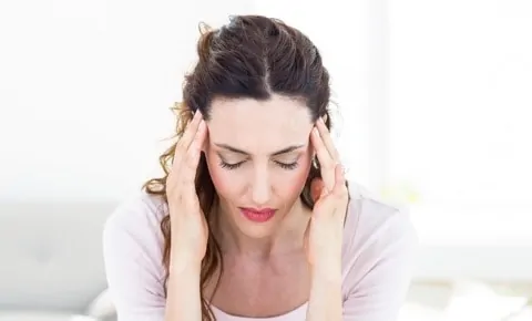 A woman with a headache rubs her temples at an emergency room in Houston, TX