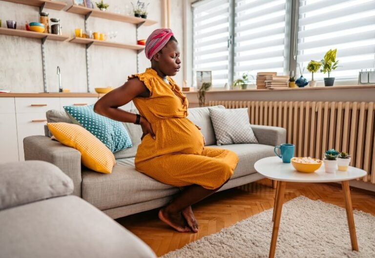 Pregnant woman holding her back due to round ligament pain