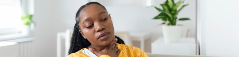 A woman suffering from allergies clutches her lymph nodes in her Houston, Texas home.