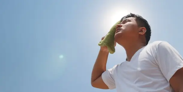 A man wipes his brow in the Houston, TX sun