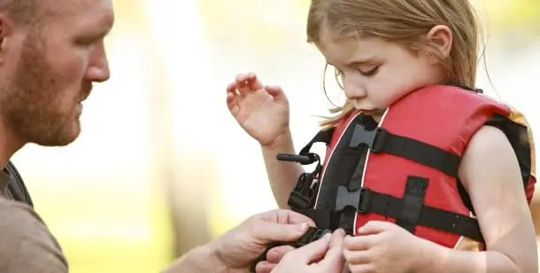 A father buckles a life jacket on his daughter to protect her from drowning in Houston, TX