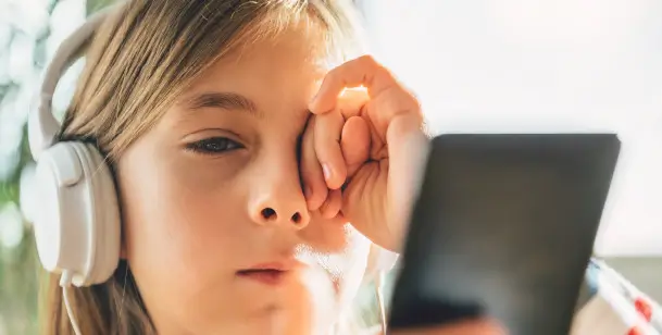 A girl with headphones rubs her eye in Houston, TX