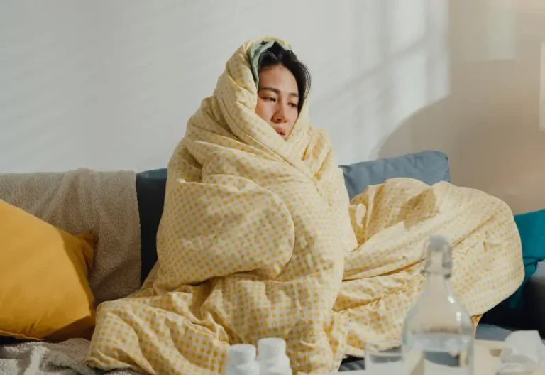 A woman with pneumonia huddles in a blanket on her couch in Houston, TX