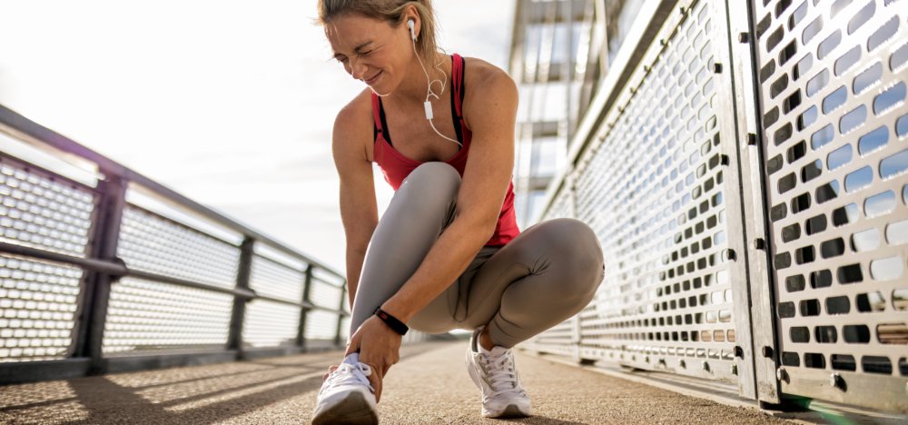 A female winces while touching her ankle on a run in Houston, TX