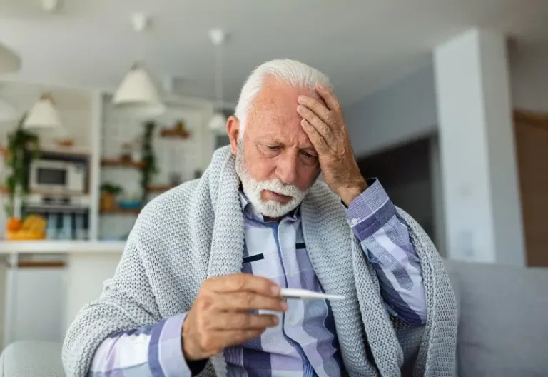 A man with a blanket holds his head and takes his temperature in Houston, TX