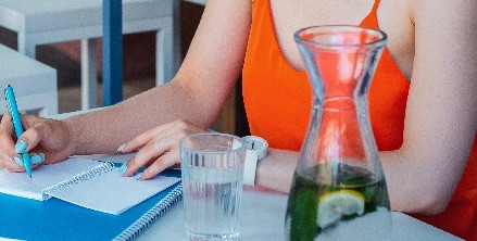 A woman writes in a notepad while drinking water in Houston, TX